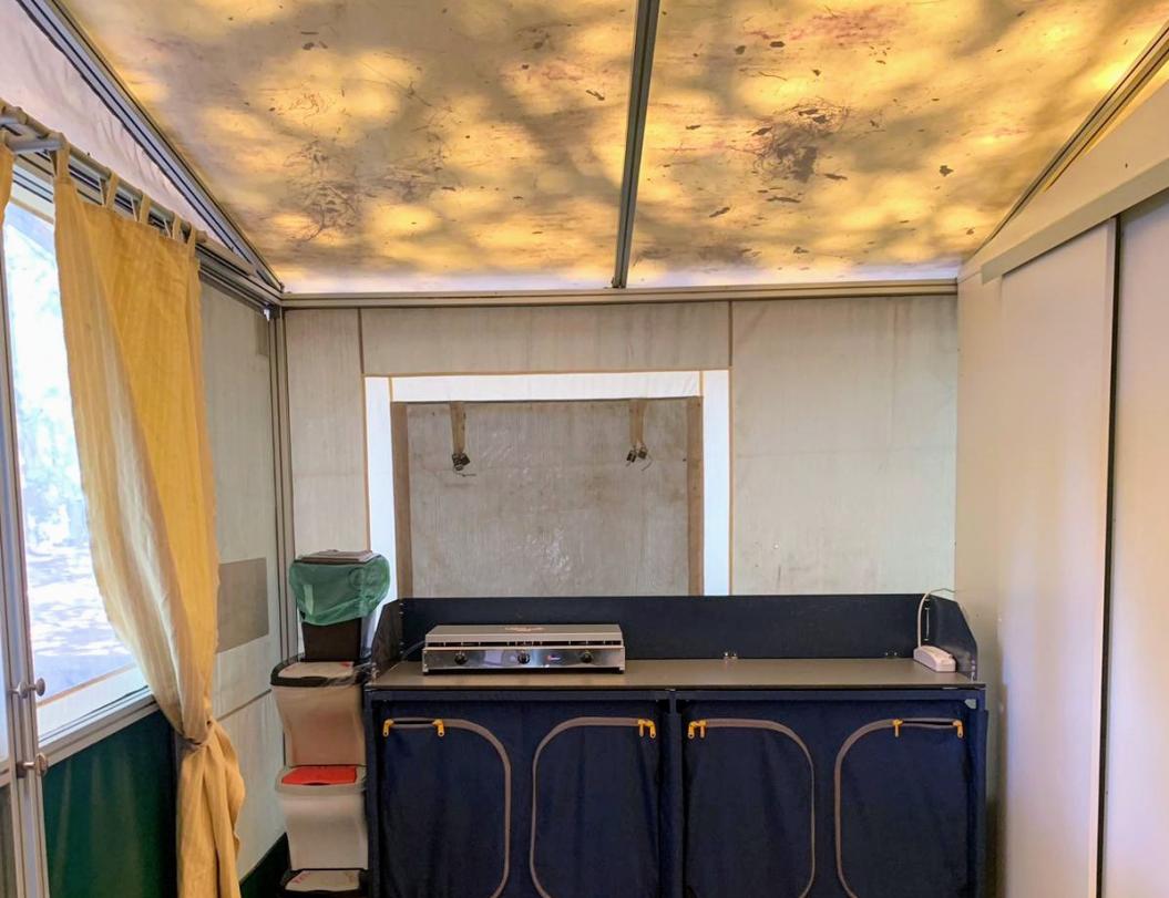 Cucina mobile con fornello a gas e armadietti, tende gialle.